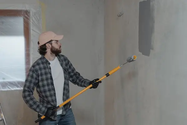 Painter rolling grey paint onto an interior wall in Tallahassee
